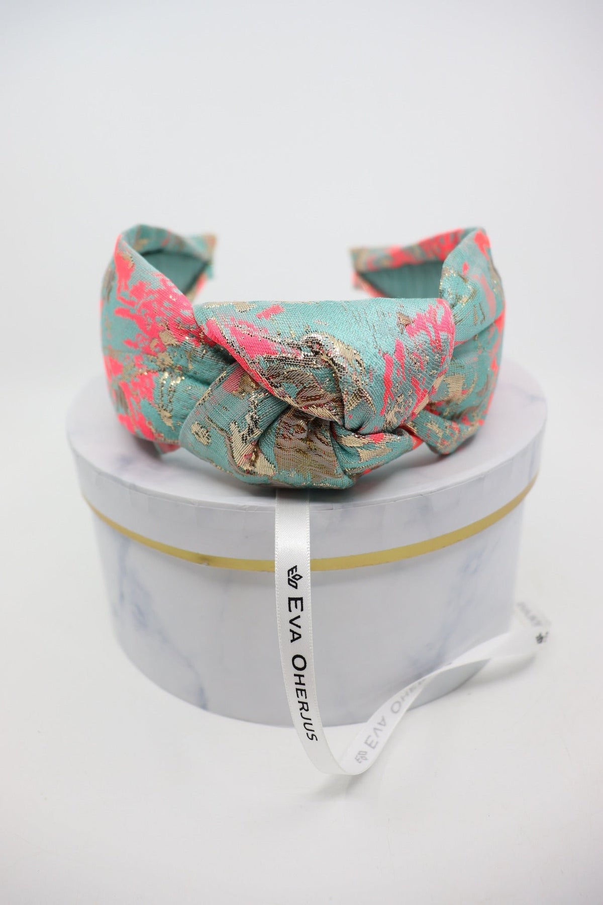 3. Eva Oherjus Knot Headband Misty shown on luxury hat box with brand name tag