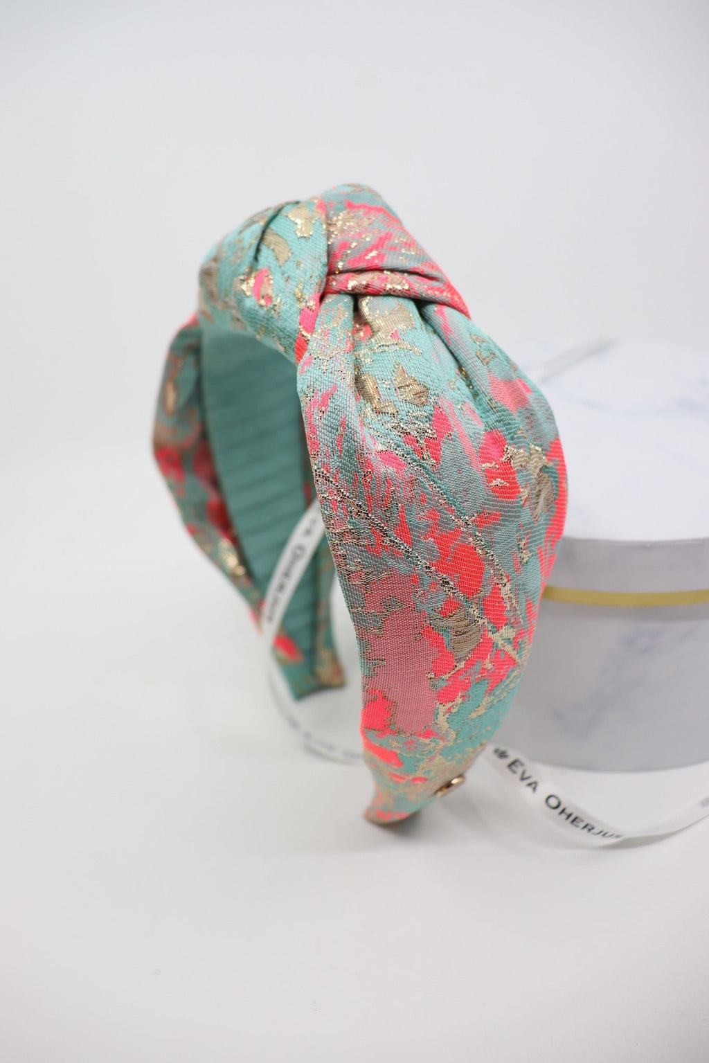 2. Eva Oherjus Knot Headband Misty with vibrant abstract spots in neon pink, gold, and mint green on display