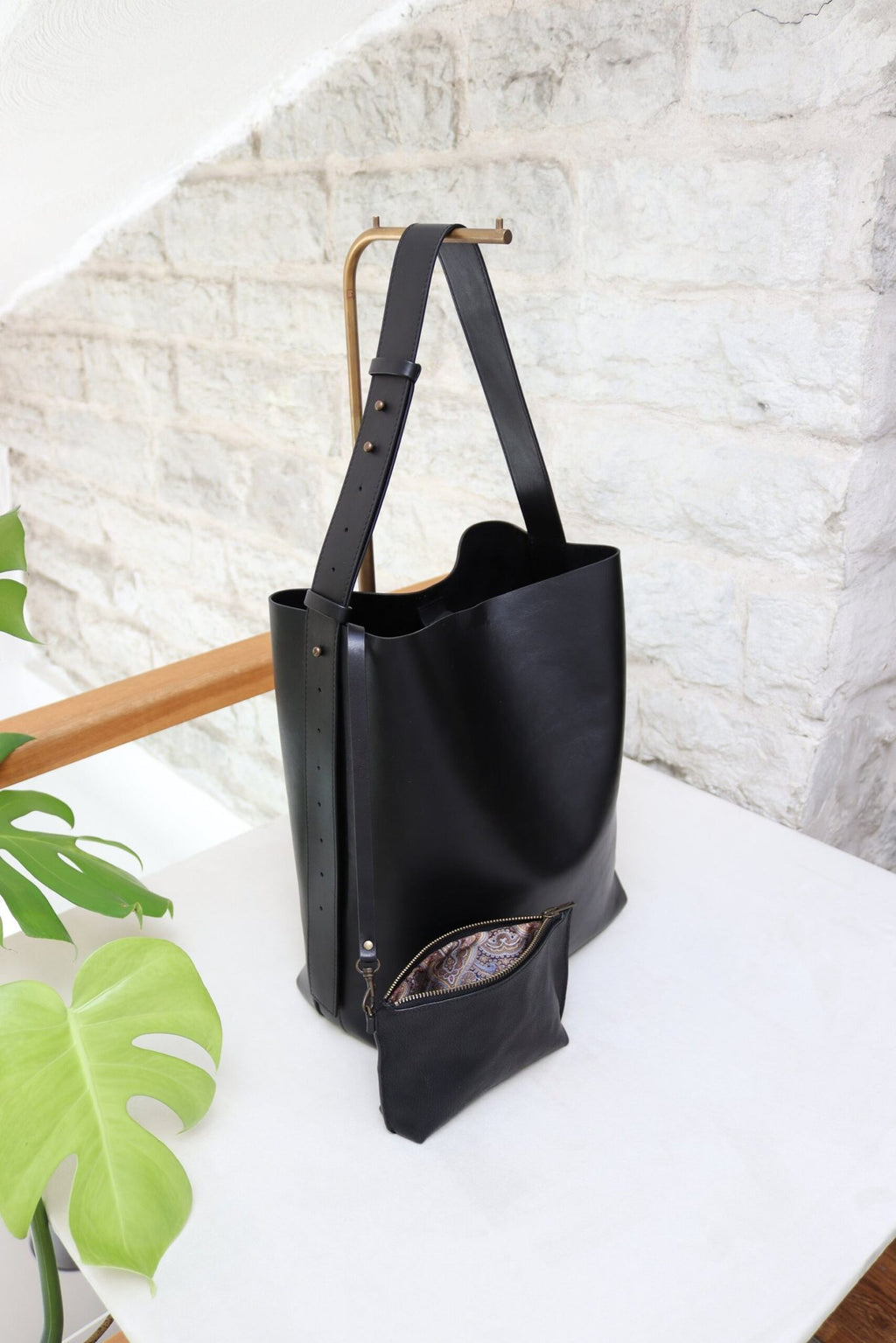 6. Tairi Roosve black leather tote with removable clutch displayed on table, showing press stud closure and design