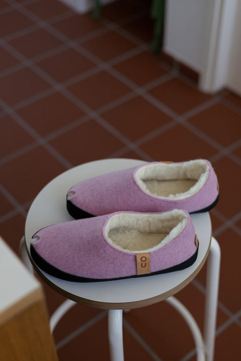 3. TOKU Budapest light pink lambswool slippers on stool, showing interior lining and brand tag