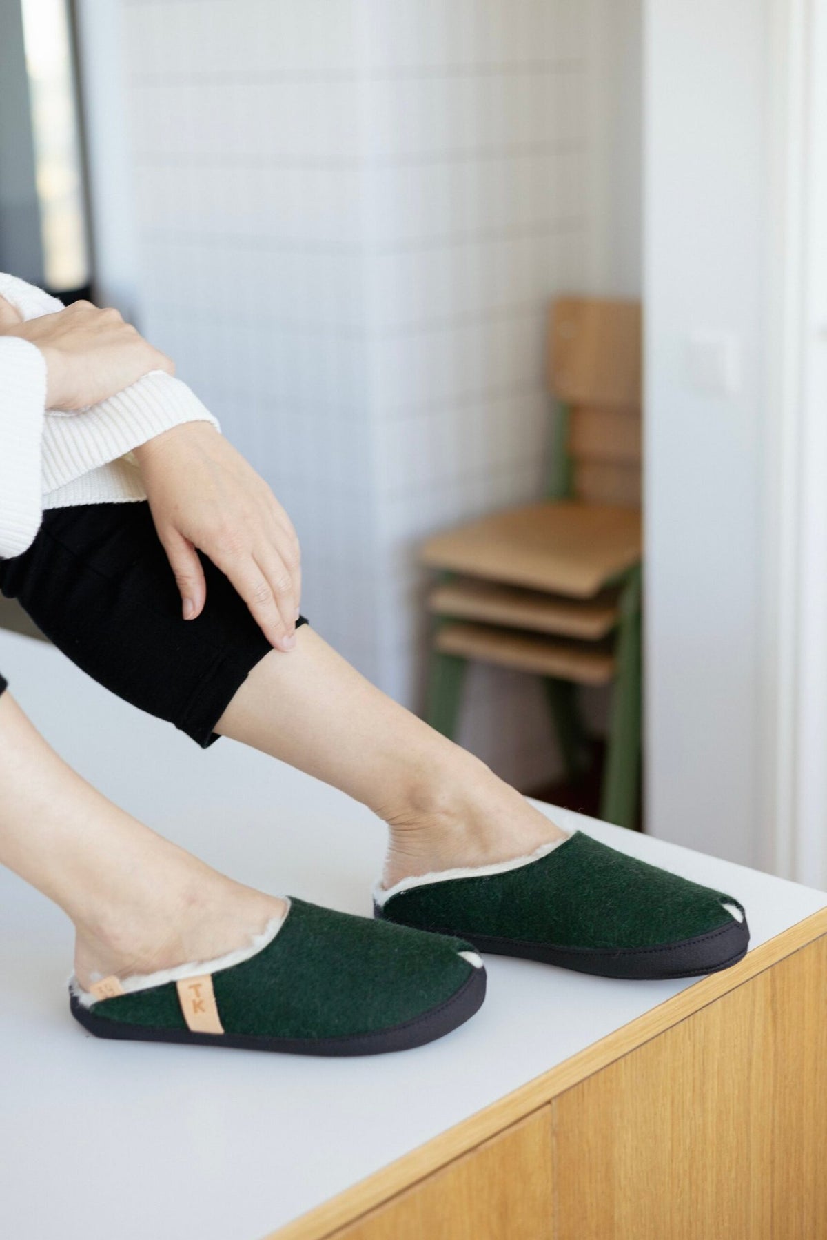 1. Unisex dark green TOKU Brussels slippers by Omaking worn by a woman in a cozy home setting