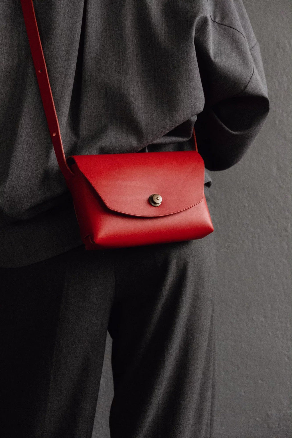 1. Women's red leather clutch bag by Mirgoods worn crossbody, shown in lifestyle setting