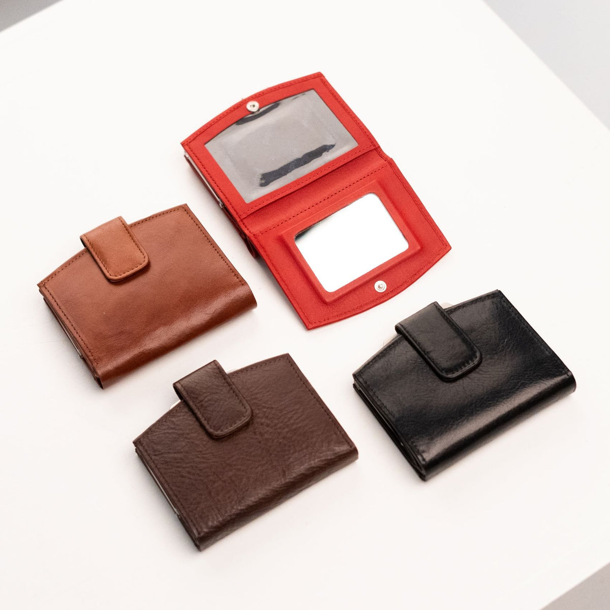 2. Open view of Papillon women's leather wallet in red, showing mirror and card slots, with other colors closed