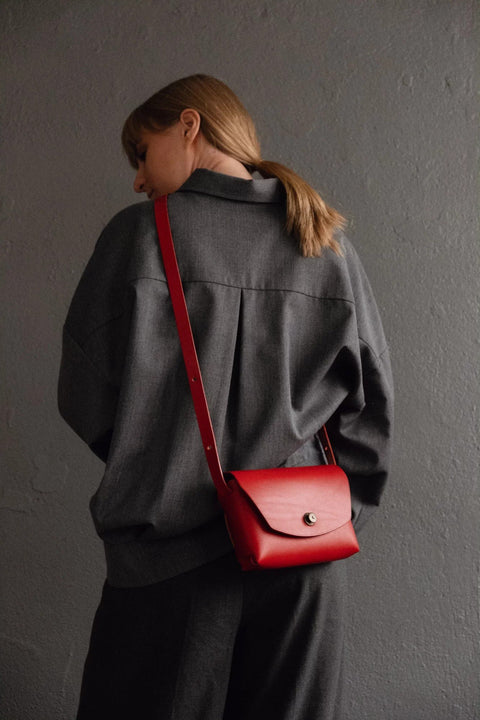 2. Women's red Mirgoods clutch bag styled with grey outfit, shown from the back