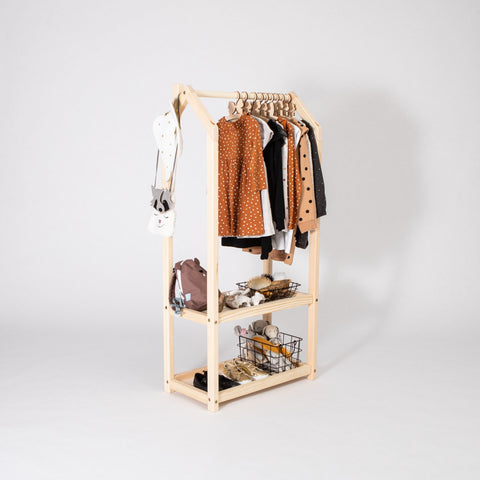 1. Natural wood house-shaped clothing rack with children's clothes and storage baskets in a room setting