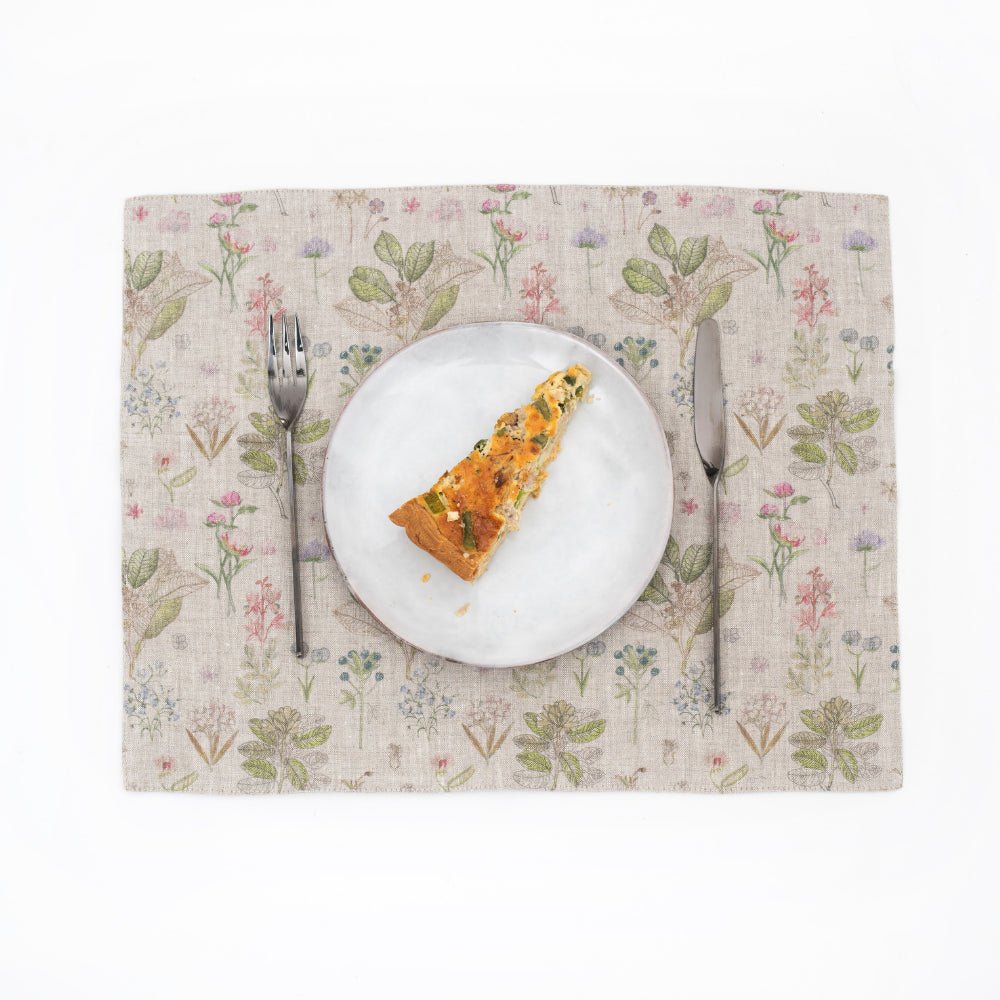 1. Floral print linen placemat with a slice of quiche on a white plate, accompanied by a fork and knife
