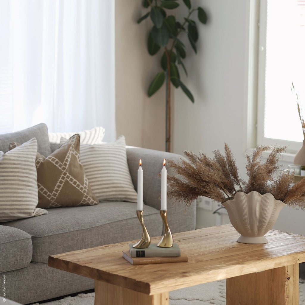 3. Living room with grey sofa featuring striped and geometric Linen Tales cushion covers, wooden coffee table, and decorative plants