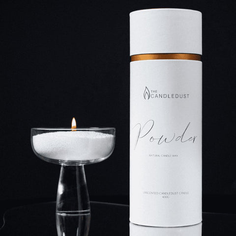 3. Studio image of Candledust powdered candle in a glass holder next to packaging