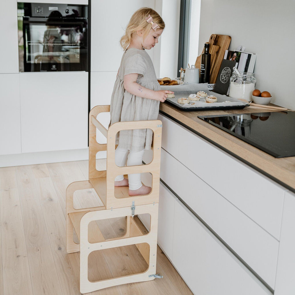 10. Child using natural wood kitchen tower as a step stool to reach kitchen counter