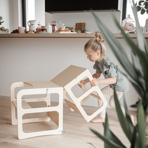 2. Child converting natural wood kitchen tower into table and chair set in a modern kitchen