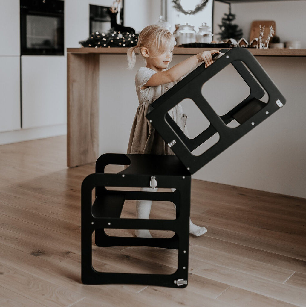 3. Girl transforming black kitchen tower into table and chair set in a festive kitchen setting