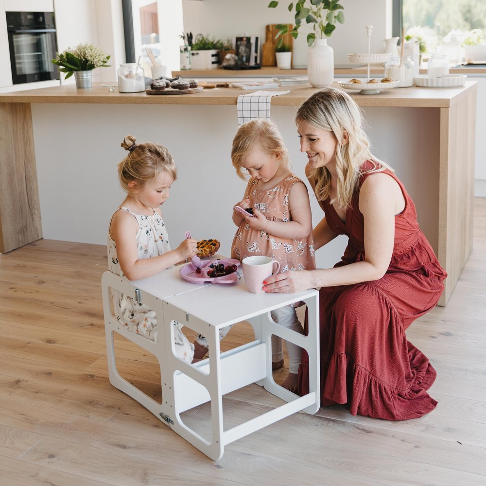 6. Two children and a woman using white kitchen tower as a table set for snacks in a bright kitchen