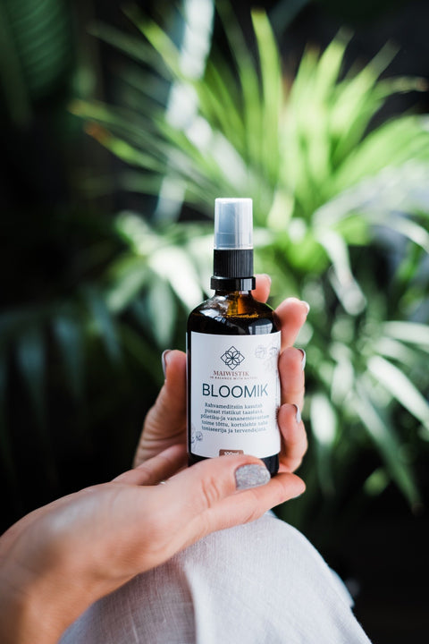 1. MaiWistik BLOOMIK 2in1 Body and Massage Oil 100ml held by a woman in a natural setting