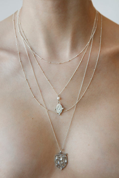 2. Close-up of women's Morning Star Necklace in silver by New Vintage by Kriss, layered with other necklaces