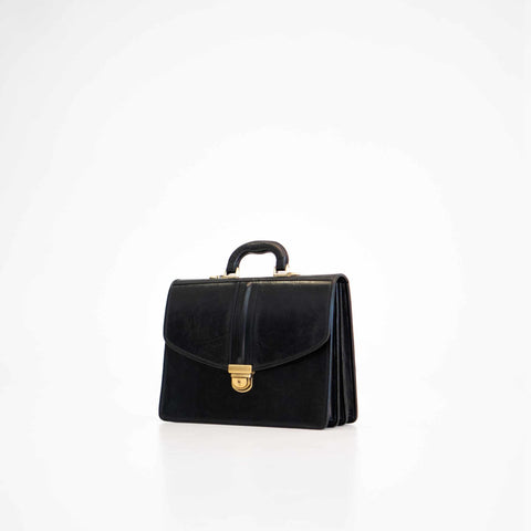 1. Papillon Briefcase No. 20 in black premium leather, studio shot showing front with gold clasp and handle