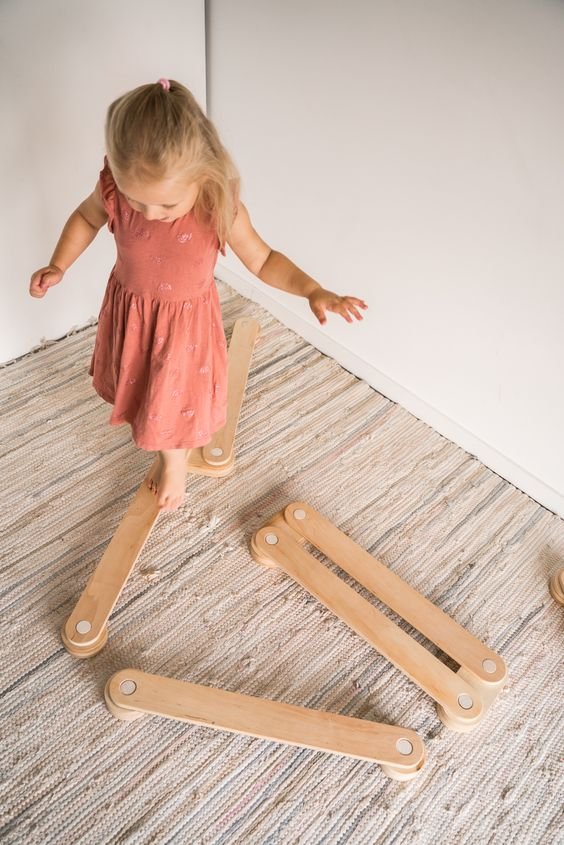 6. Child in pink dress stepping on Ewart Woods wooden balance beams