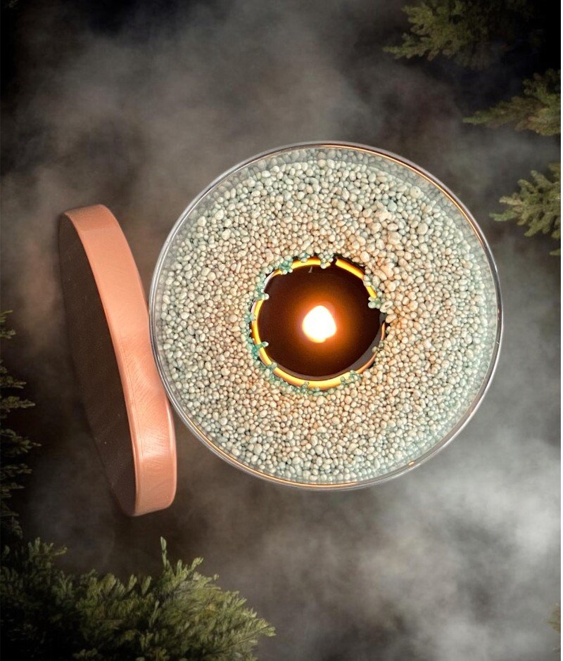 3. Top view of lit Candledust emerald powder candle in glass with open lid, surrounded by mist