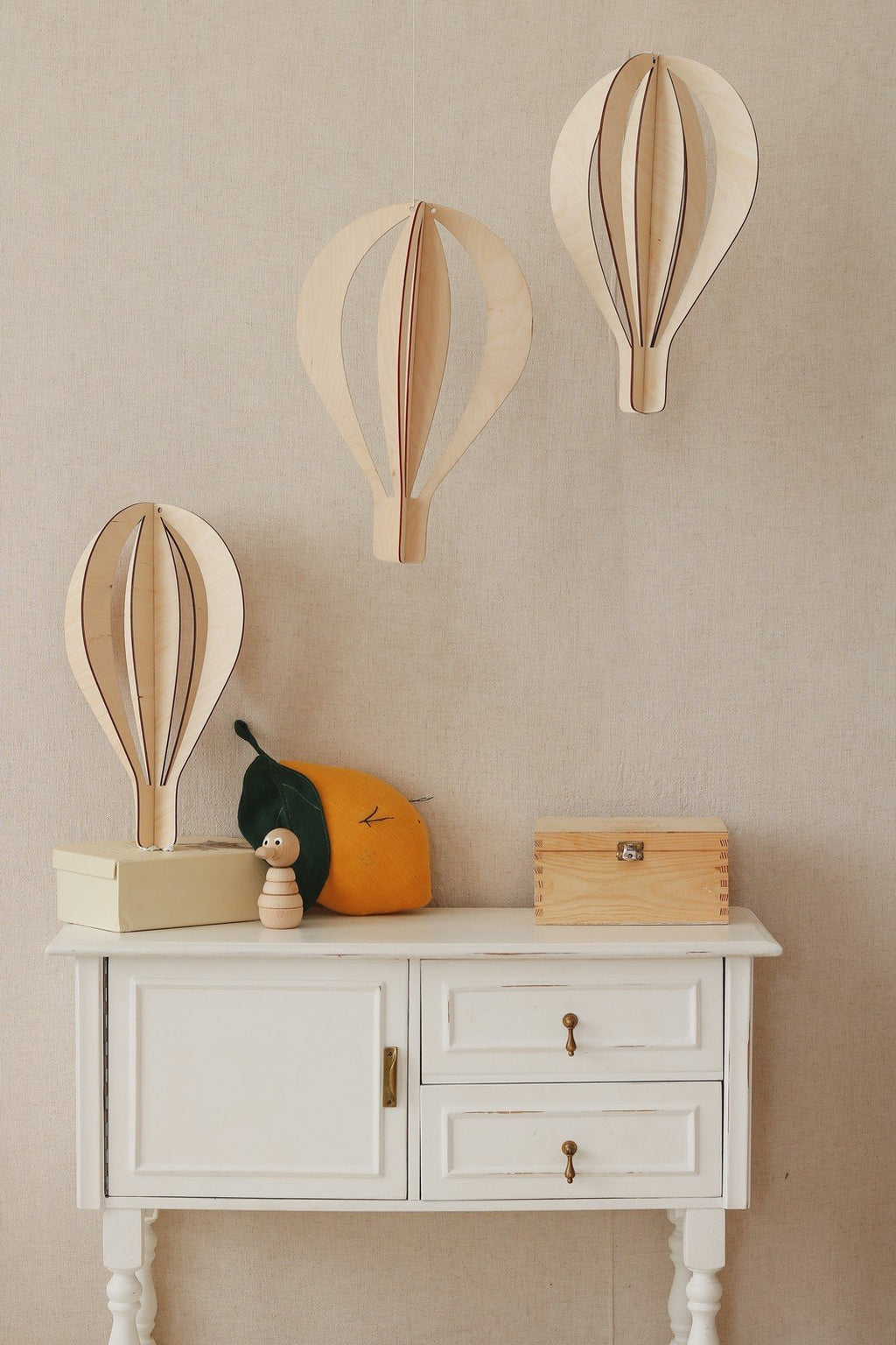 4. Three birch plywood hot air balloon decorations on beige wall above cabinet with wooden toys