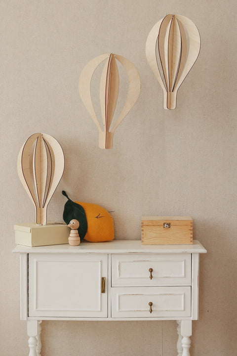 4. Three birch plywood hot air balloon decorations on beige wall above cabinet with wooden toys