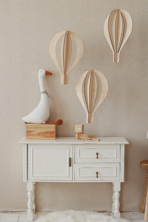 1. Set of three birch plywood hot air balloon decorations on beige wall above white cabinet with decorative goose