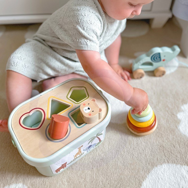 7. Baby playing with Woopie Let's Go Green 3in1 toy set, focusing on shape sorting and stacking