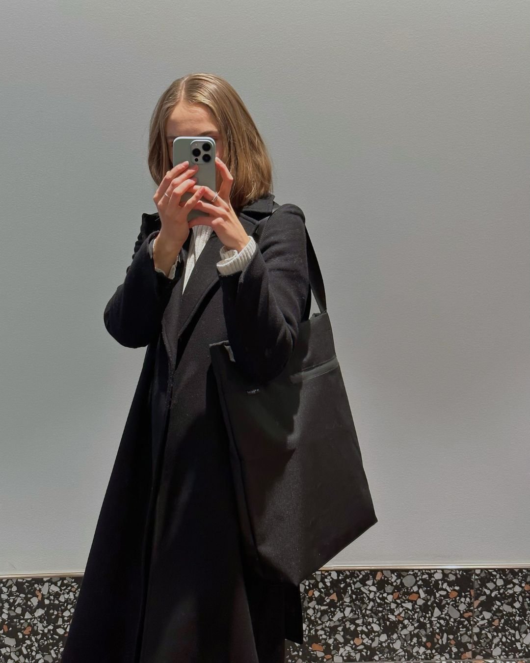 1. Woman in black coat holding Nordhale VIK Tote Bag in lifestyle setting