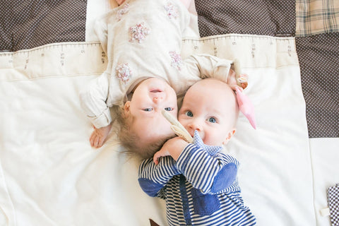 1. Two babies lying on patterned blanket, one holding Karloova magic wand