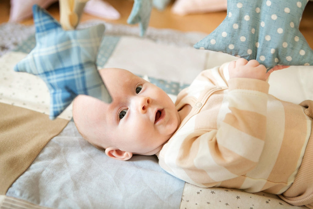 6. Baby lying on play mat reaching for blue starlet toys