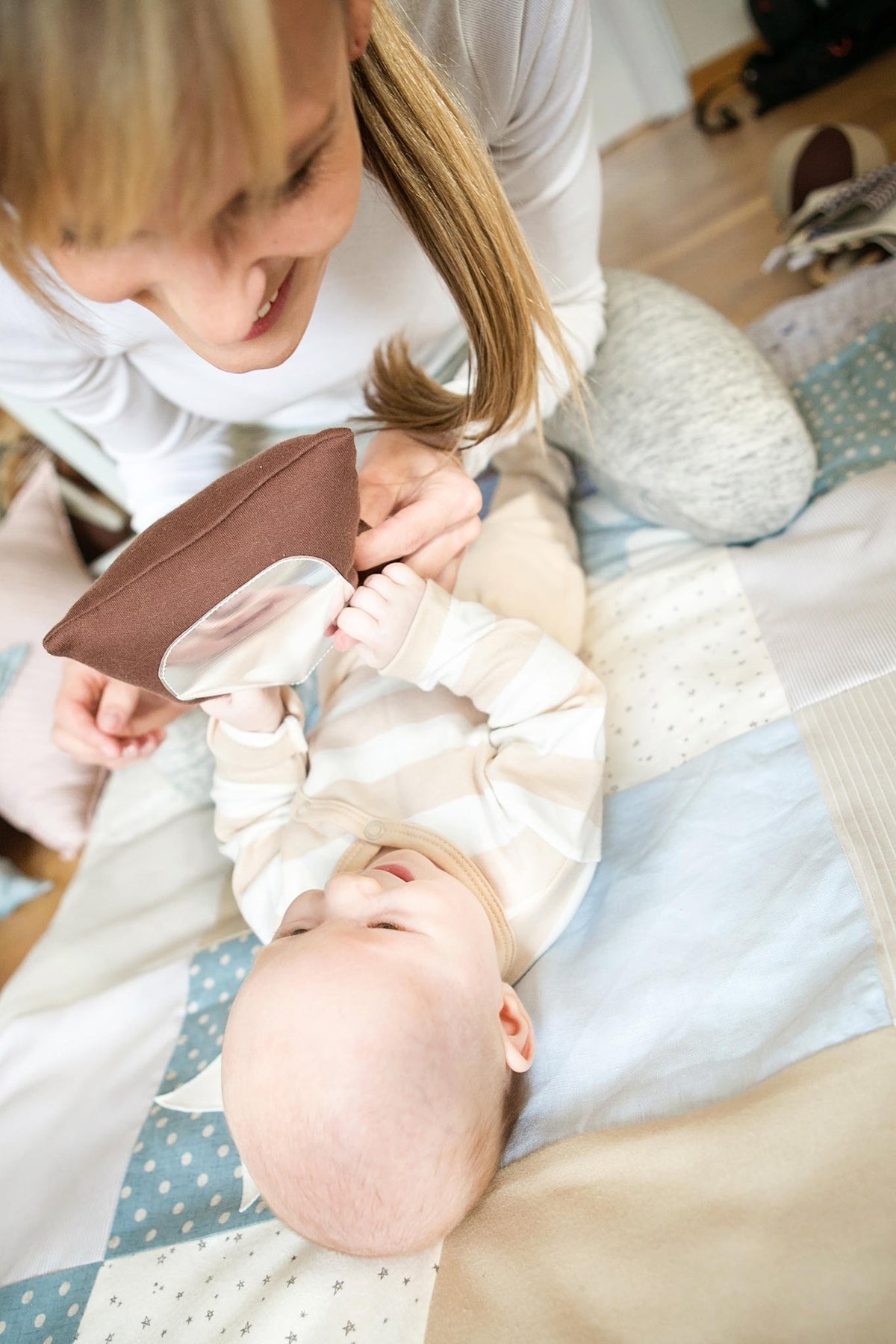 1. Smiling adult showing baby the mirror on Karloova Pillow Heap's brown pillow