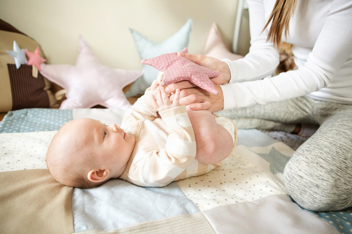 2. Baby playing with pink star toy on Karloova activity mat with adult assistance