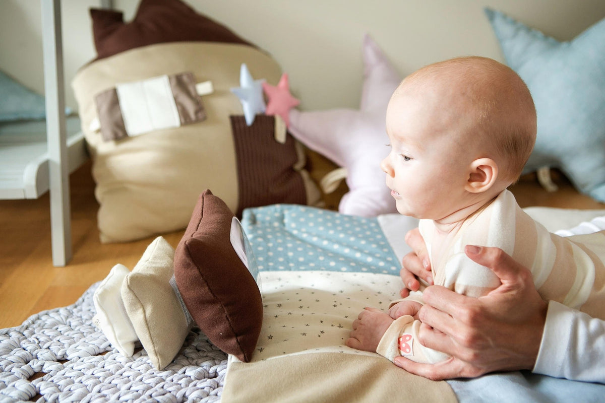 1. Baby supported by adult, interacting with Karloova Pillow Heap on play mat