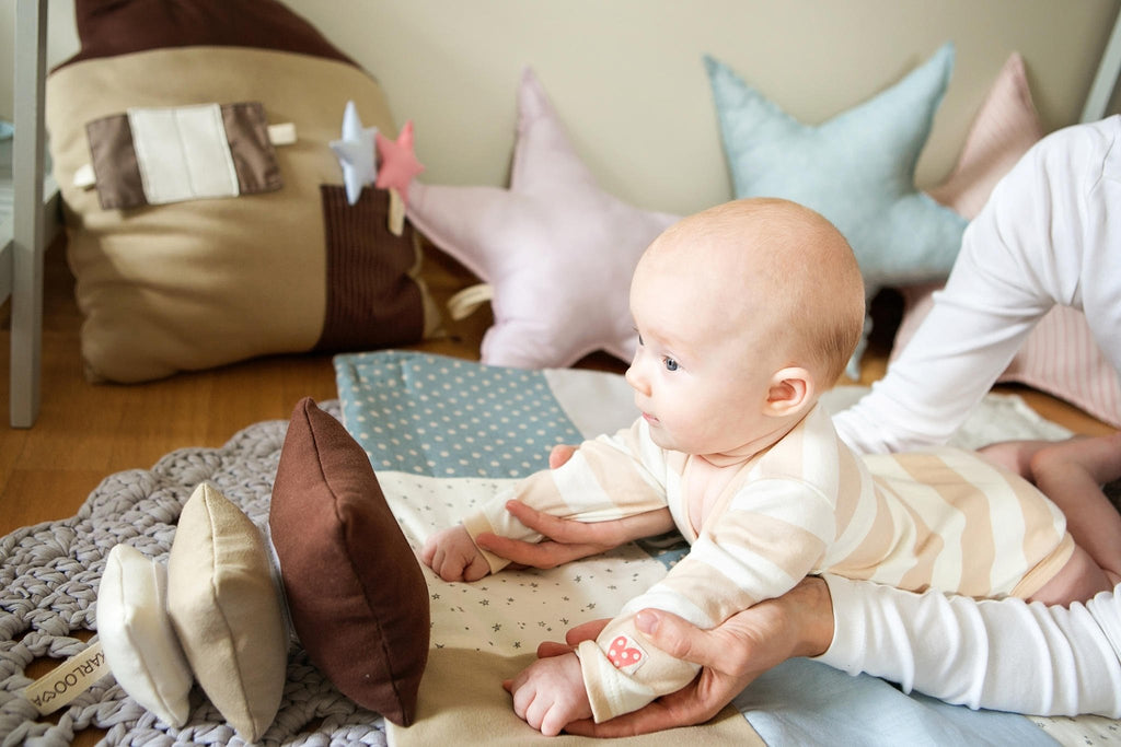 1. Baby interacting with Karloova Pillow Heap on play mat, supported by adult