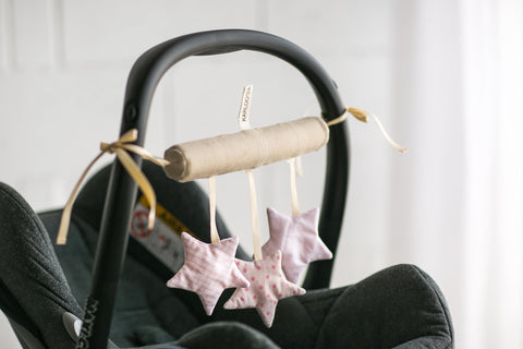 1. Pink star-shaped baby crib toy attached to a car seat handle, featuring three stars with crinkle and ring sounds, enhancing fine motor skills and auditory development.