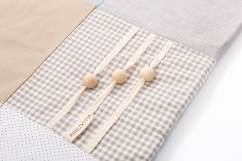 3. Detail of Karloova activity mat showing beige and white checkered fabric with movable wooden buttons