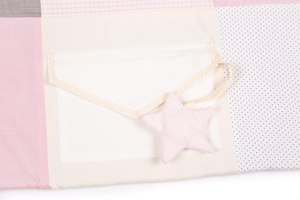 3. Close-up of pink striped star toy attached to envelope pocket on activity mat