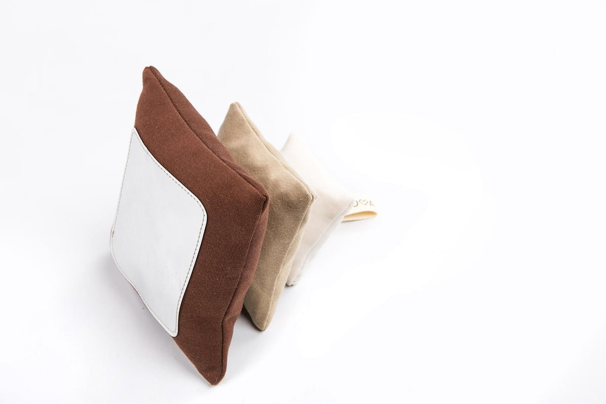 2. Karloova Pillow Heap with brown, beige, and white pillows stacked on white background