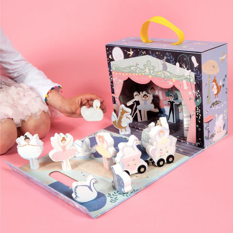 1. Child playing with Floss & Rock enchanted playbox featuring wooden ballerinas and swans on a pink background