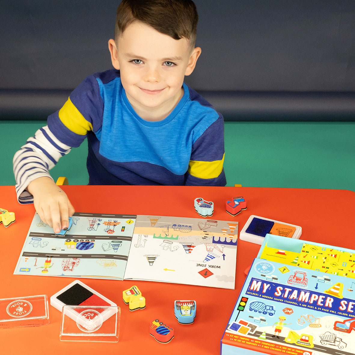 1. Child using My Stampler Set with booklet and stamps on a red table