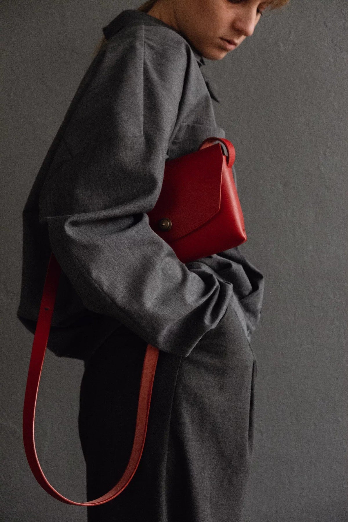 3. Close-up of red leather clutch bag by Mirgoods held by woman, highlighting compact design
