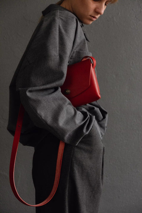 3. Close-up of red leather clutch bag by Mirgoods held by woman, highlighting compact design