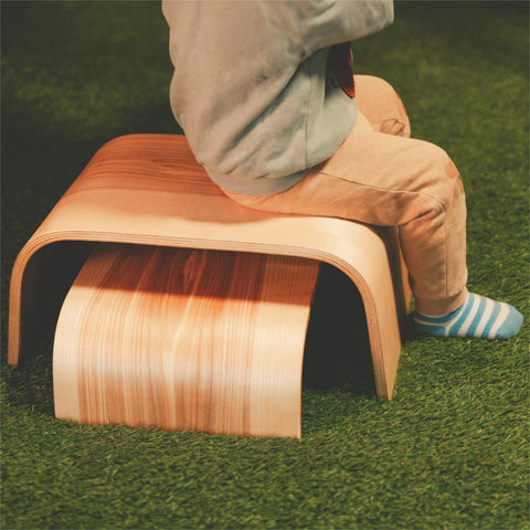 2. Child sitting on wooden step stool on grass wearing striped socks and beige pants