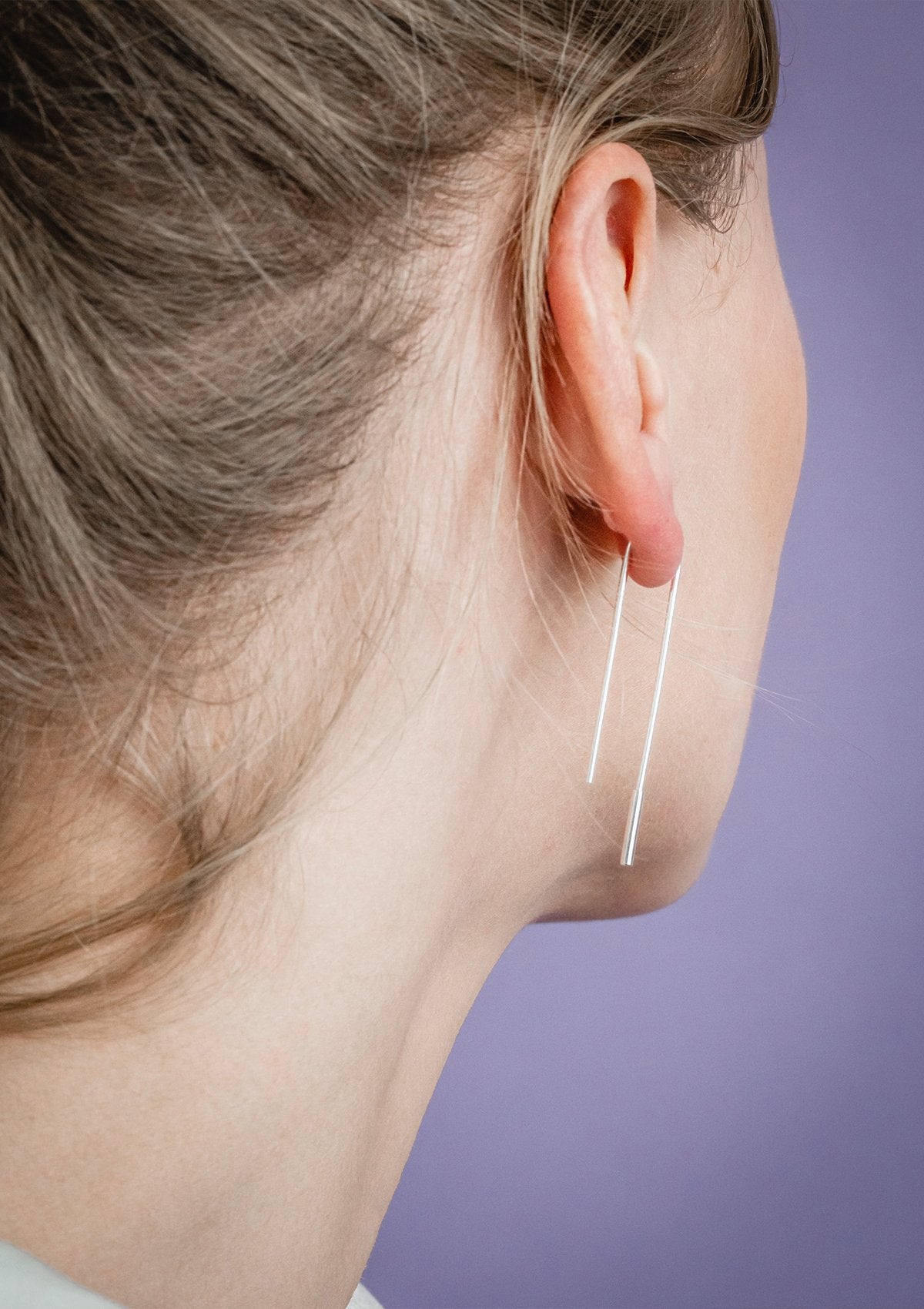1. Women's minimalist U-shaped silver earrings by Maarja Palu, shown worn in lifestyle setting