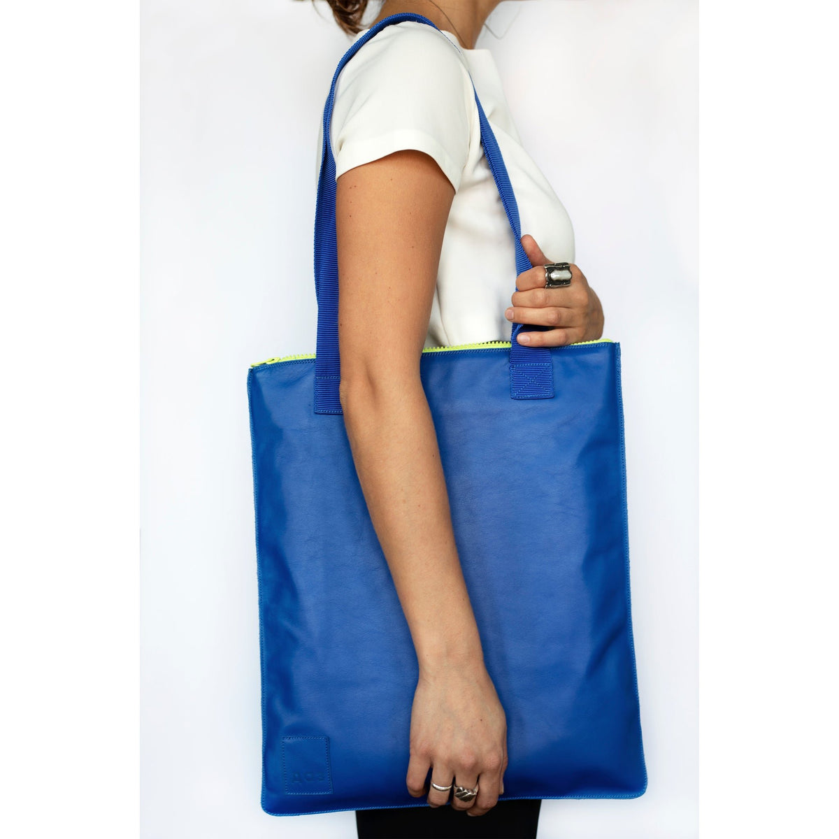 2. Side view of woman carrying Daz Studio royal blue leather tote with blue nylon straps