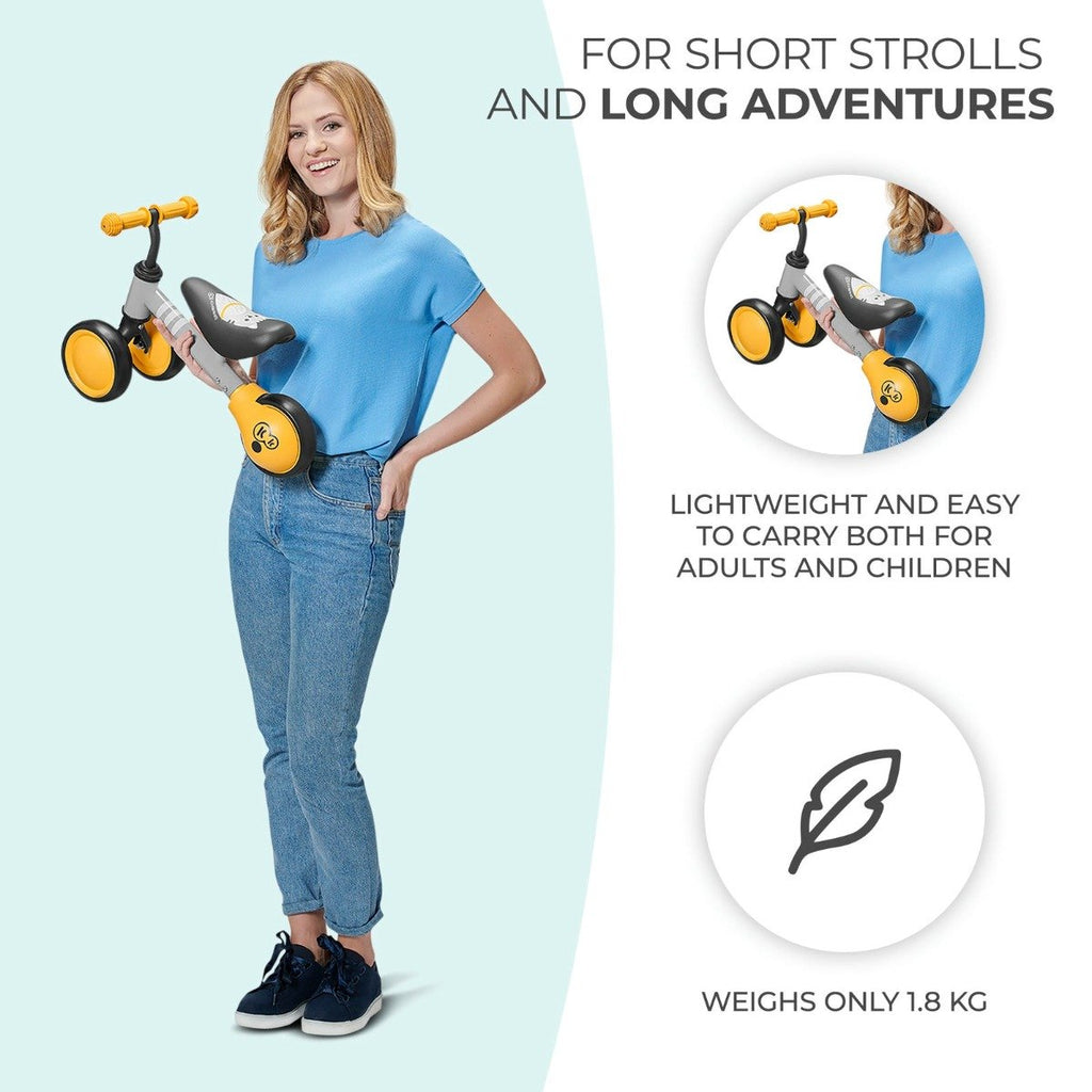 1. Woman holding yellow Kinderkraft CUTIE balance bike highlighting lightweight design