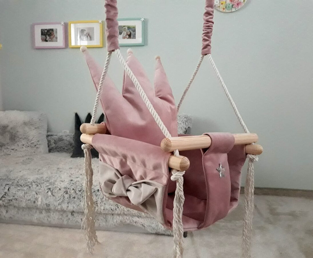 1. Dusty pink crown-shaped cushion swing in children's room with plush sofa and framed pictures on wall