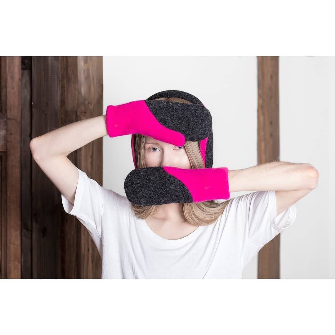 2. Woman posing with HERTTA neon pink and dark grey felted wool mittens indoors