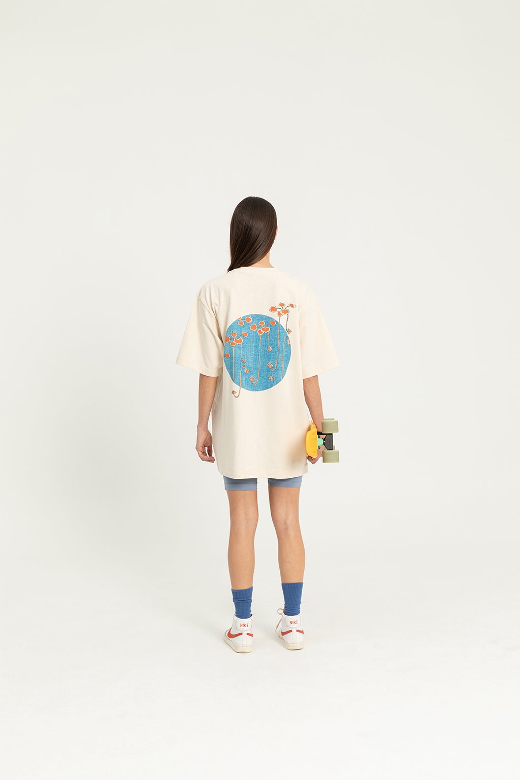 8. Women's 'Bijutsu Sekai' t-shirt by Watanabe Seitei, shown from back, worn by female model with skateboard, lifestyle setting