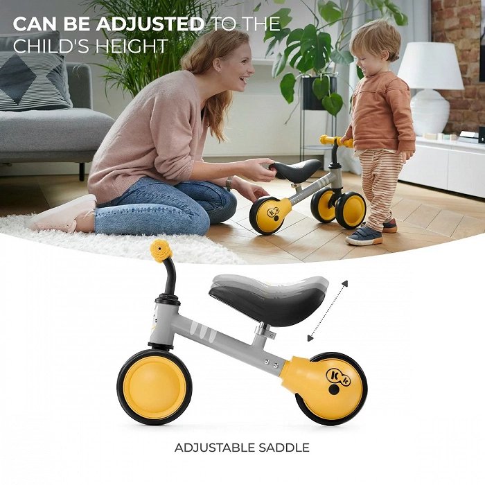 5. Child and parent adjusting saddle height on yellow Kinderkraft CUTIE balance bike indoors