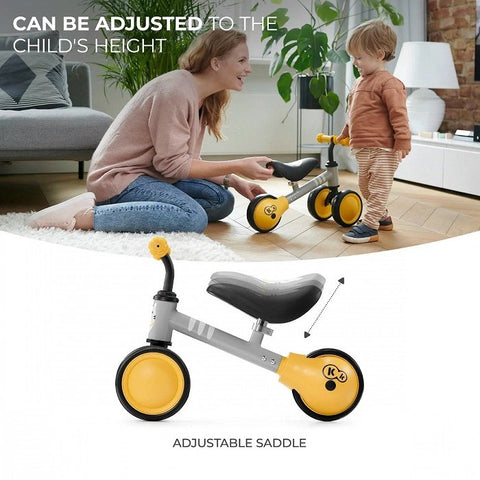 5. Child and parent adjusting saddle height on yellow Kinderkraft CUTIE balance bike indoors