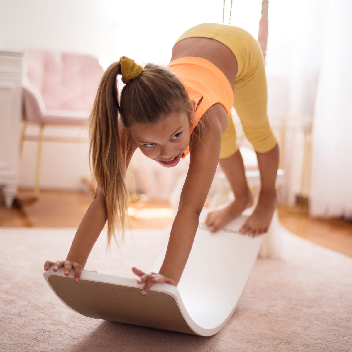 1. Girl balancing on white board in living room, wearing yellow outfit, showcasing playfulness